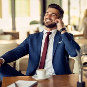 happy mid adult businessman using cell phone on a coffee break in a cafe.